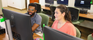 Two students looking at a computer monitor